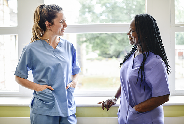 NHS staff in scrubs stand talking in a corridor